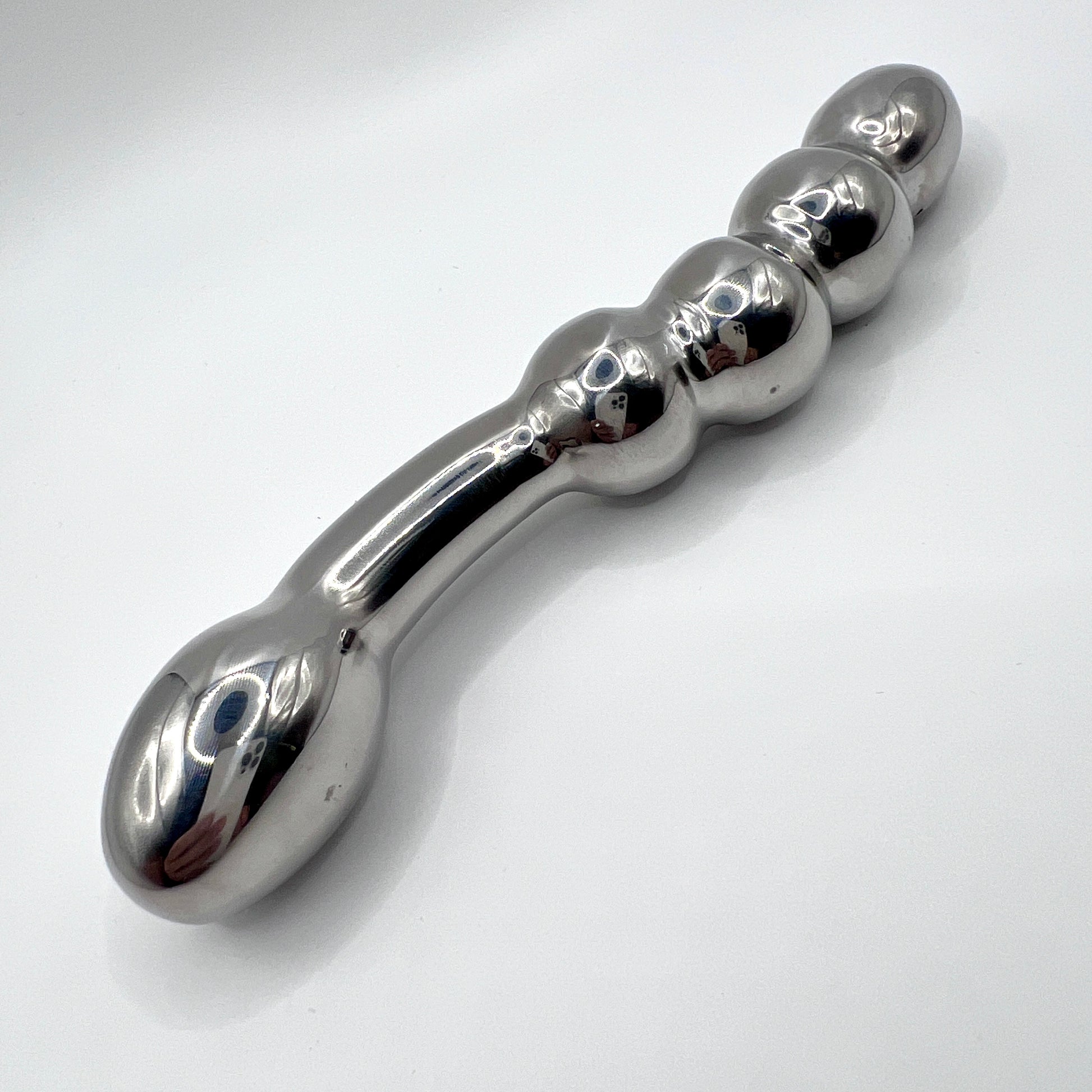 Metallic object with a handle and spherical ends on a white background