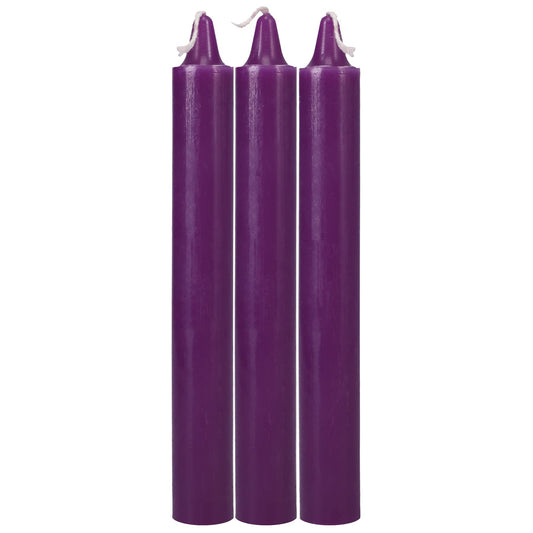 Three purple candles with white wicks on a white background