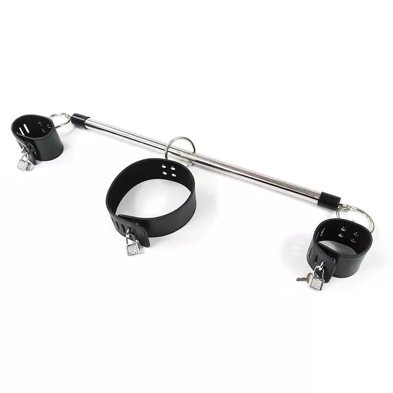 A metal and black restraint set featuring a long silver bar, a black collar, and two black cuffs with small silver padlocks and keys, photographed on a plain white background.