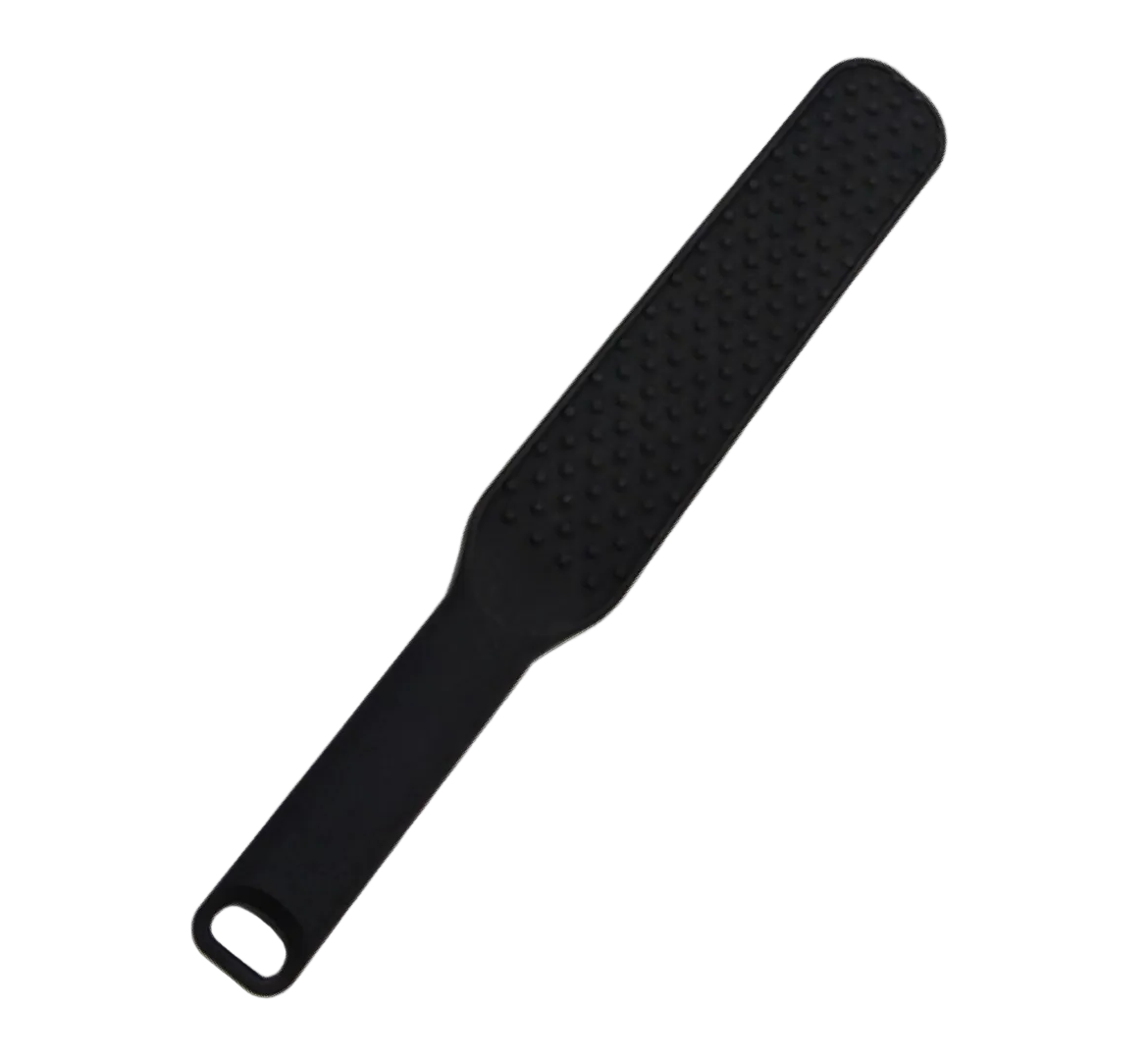A black silicone foot scrubber with a textured scrubbing surface and a hanging loop at the end, shown on a plain white background.