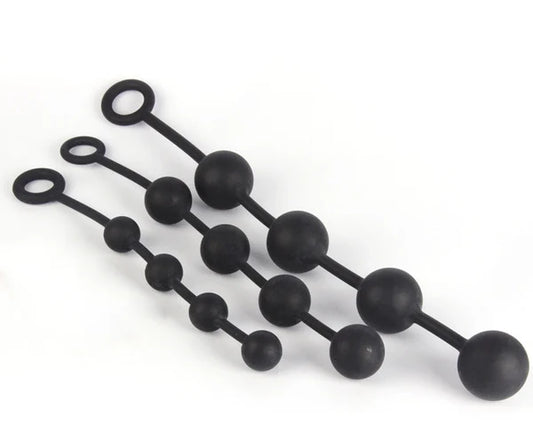 Three black silicone butt plugs with varying bead sizes and looped ends, arranged diagonally on a plain white background.